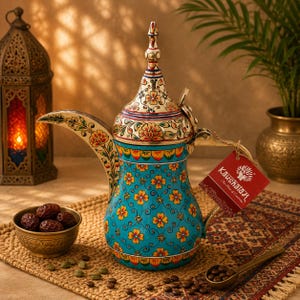 May include: A turquoise metal coffee pot with a pointed lid, featuring hand-painted orange and yellow floral patterns, a long curved spout, and a gold-toned handle. A red tag with the white text Kaushalam is attached to the handle.