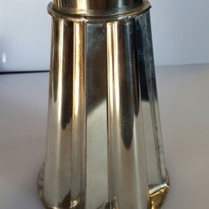 May include: A silver metal cake mould with a fluted design. The mould is shaped like a cone and has a smooth, shiny surface.