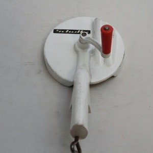 May include: White metal hand crank food mill with a red handle and the word "Schall" printed on the side.
