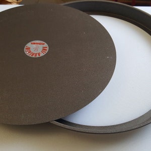 Puede incluir: Un molde para pasteles redondo de metal gris con fondo extraíble. El molde tiene una etiqueta que dice "WIL-ADJUST  DOUBLE".