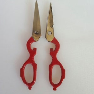May include: Red kitchen shears with a bottle opener feature. The blades are stainless steel.