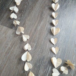 May include: A garland of paper hearts made from book pages. The hearts are strung together with white thread and hang in a decorative pattern.