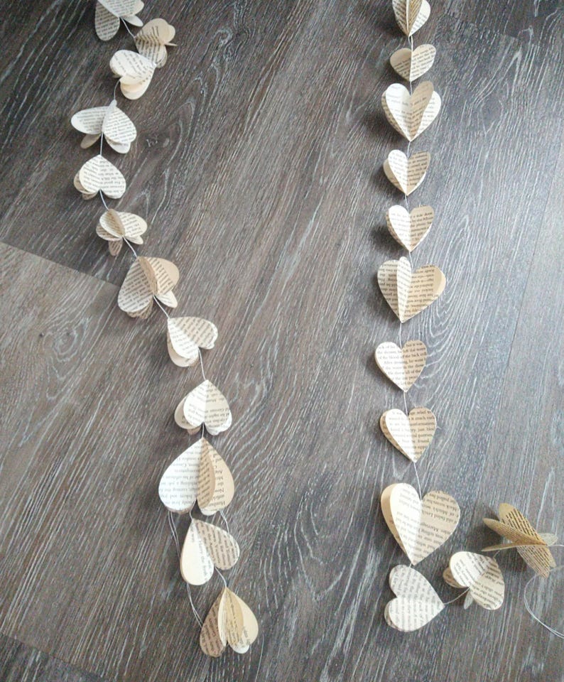 May include: A garland of paper hearts made from book pages. The hearts are strung together with white thread and hang in a decorative pattern.