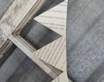May include: A partially assembled, distressed wooden picture frame with triangular paper cutouts. The paper cutouts are from a book, with visible text. The frame has a weathered, rustic appearance.