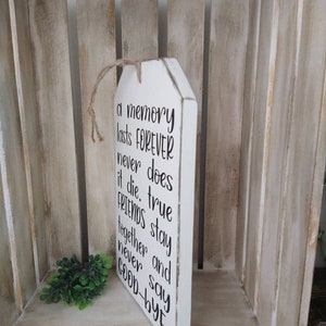May include: White wooden sign with the text "a memory lasts FOREVER never does it die. true FRIENDS stay together and never say GOOD-BYE." The sign has a jute rope for hanging.
