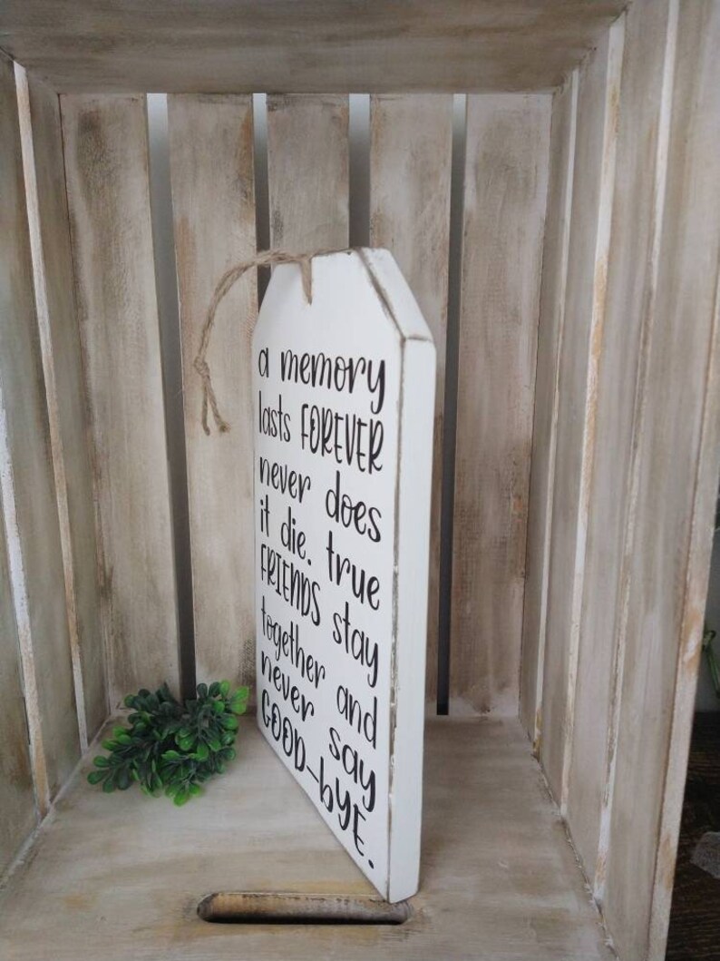 May include: White wooden sign with the text "a memory lasts FOREVER never does it die. true FRIENDS stay together and never say GOOD-BYE." The sign has a jute rope for hanging.