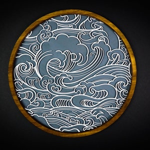 May include: A circular wooden frame featuring a blue and white wave pattern. The waves are stylised and intricate, creating a dynamic and flowing design.
