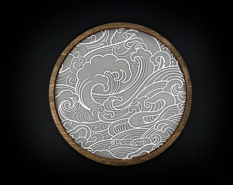 May include: A round wooden tray featuring a white wave pattern design. The tray is crafted from wood and has a natural finish.
