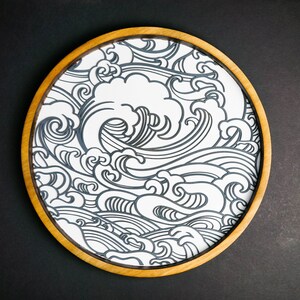 May include: A round wooden tray with a white background and a black and white wave pattern.