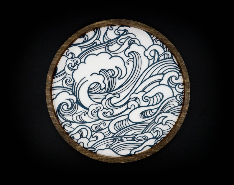 May include: A round wooden coaster featuring a blue and white wave design. The coaster is ideal for protecting surfaces from scratches and spills.