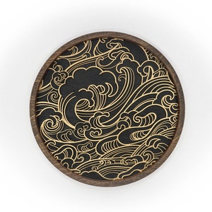 May include: A round wooden coaster with a black background and a gold wave pattern.