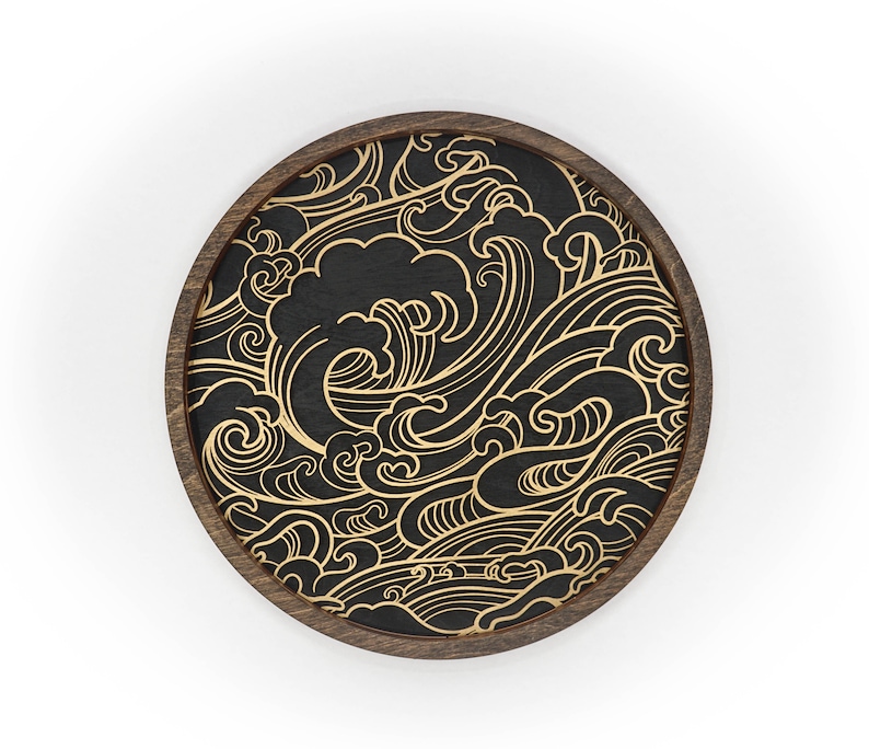 May include: A round wooden coaster with a black background and a gold wave pattern.
