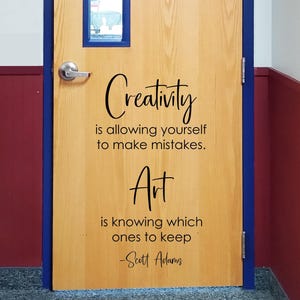 May include: A light-colored wooden door featuring a black vinyl decal with the quote: Creativity is allowing yourself to make mistakes. Art is knowing which ones to keep -Scott Adams. The door has a silver metal handle and a rectangular window.