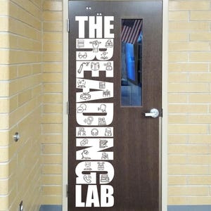 May include: A brown door with the words "THE READING LAB" in white, vertically aligned. The text is accompanied by various white line-art illustrations related to reading and learning. An American flag is visible through a small window.