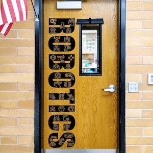 May include: A wooden door with a black vertical decal featuring the word ROBOTICS in large capital letters. Each letter is filled with small, intricate line-art icons representing technology, including gears, robots, circuit boards, and game controllers.