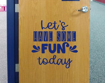 May include: A light brown wooden door featuring a dark blue vinyl decal with the text Let's HAVE SOME FUN today. The door includes a silver metal handle and a small rectangular window at the top. The text uses a mix of script and block fonts.