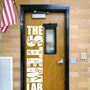 May include: A wooden door with a black frame featuring a white vinyl decal that reads THE STEM LAB. The letters are filled with various science and technology icons including a microscope, atom, gears, robot, lightbulb, and the pi symbol.