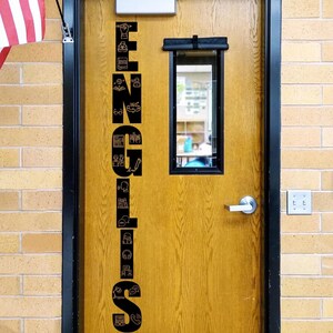May include: A wooden door with a black vertical decal featuring the word ENGLISH spelled out with various educational icons integrated into each letter. The door includes a rectangular window, a silver handle, and a metal closer at the top.