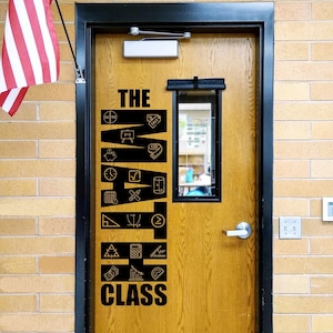 May include: A wooden door with black text that reads "THE MATH CLASS" and various math symbols. An American flag hangs to the left. The door is set in a brick wall.