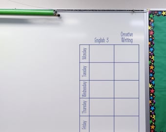 May include: A white dry-erase board featuring a blue grid with the column headers English 3 and Creative Writing, and row labels for Monday, Tuesday, Wednesday, Thursday, and Friday. A green projection screen housing is visible at the top edge.