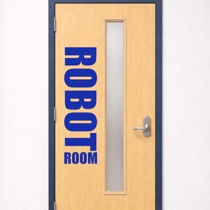 May include: A light wood-toned door with a dark blue frame, featuring a vertical rectangular frosted glass window, a silver metal lever handle, and a silver kick plate. The text ROBOT ROOM is printed in large, bold, blue capital letters on the door.