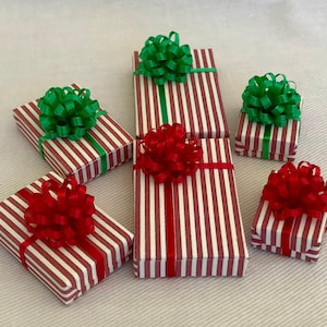 May include: Six miniature gift boxes with red and white striped paper and red or green bows. The boxes are arranged in a semi-circle on a white surface.