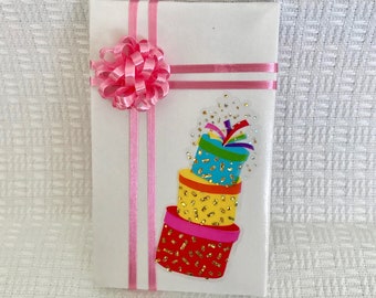 May include: A white gift box with a pink bow and a colorful sticker of stacked presents with gold glitter.
