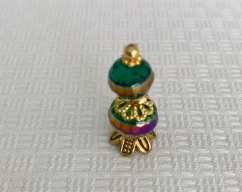 May include: A small, gold-colored, decorative stand with a green iridescent glass top. The stand has a floral design and a round base.