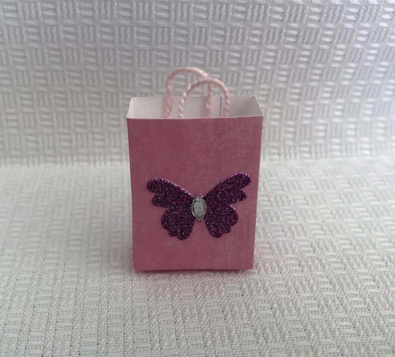May include: A small pink gift bag with a purple glitter butterfly design.