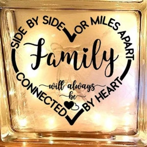 May include: A glass block with a heart-shaped design and the text "Side by side or miles apart, family will always be connected by heart".