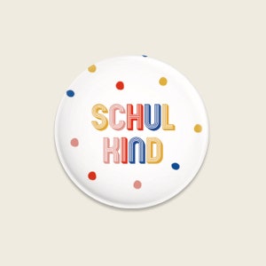 Könnte beinhalten: Runder weißer Teller mit bunten Punkten und dem Text "SCHUL KIND" in einer Retro-Schrift.