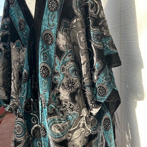 Puede incluir: Un kimono de terciopelo negro y turquesa con un patrón de paisley y detalles de cuentas.