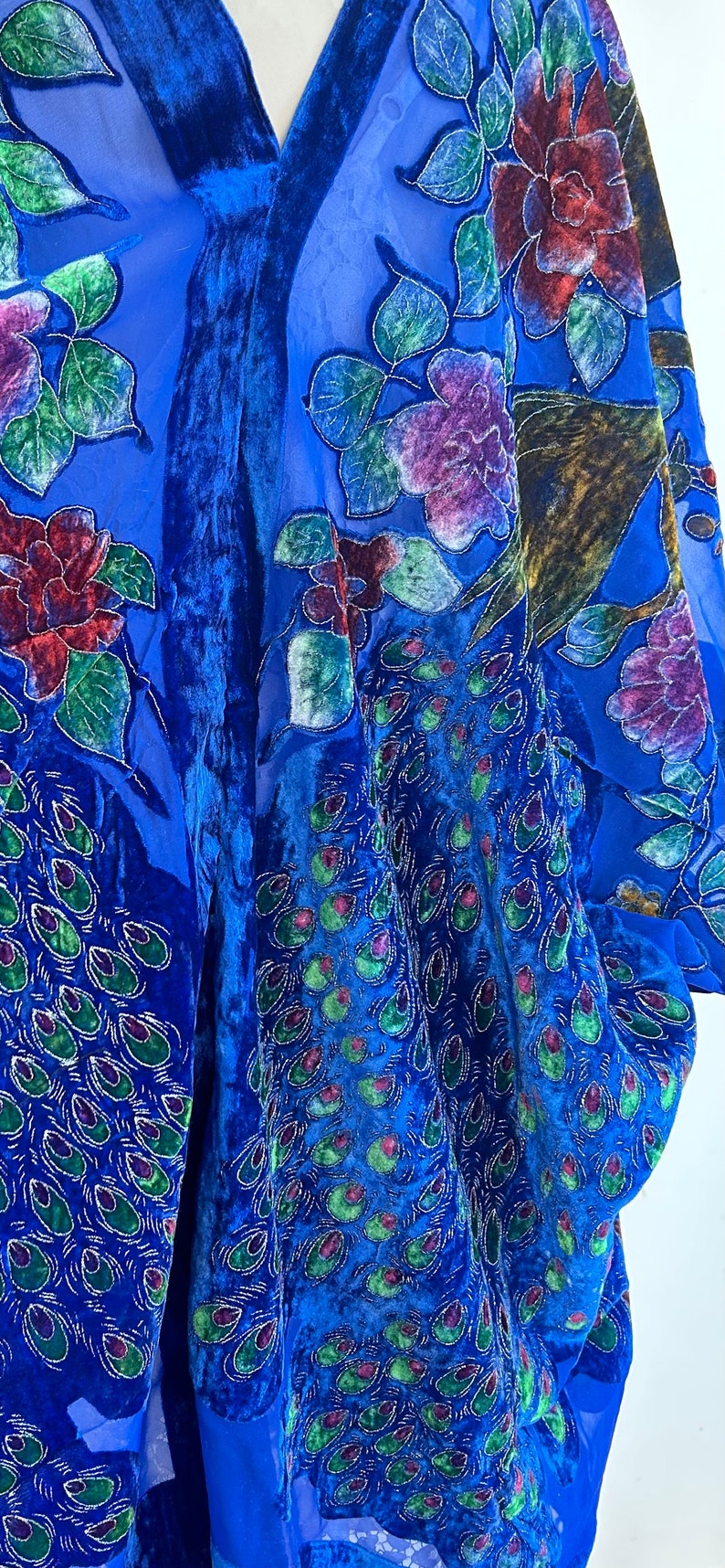 May include: A blue velvet kimono with a sheer overlay featuring embroidered peacocks and floral designs in shades of green, purple, and red.