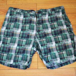 以下が含まれることがあります： 緑、白、青の格子柄のショートパンツで、ボタンフライです。