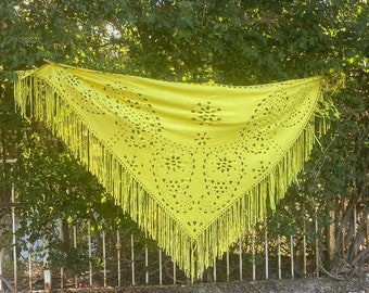 May include: A bright yellow crochet shawl with a fringe border and a delicate floral pattern.