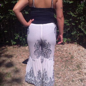 May include: White maxi skirt with a black paisley print. The skirt has a ruffled hem and is made of a sheer fabric.