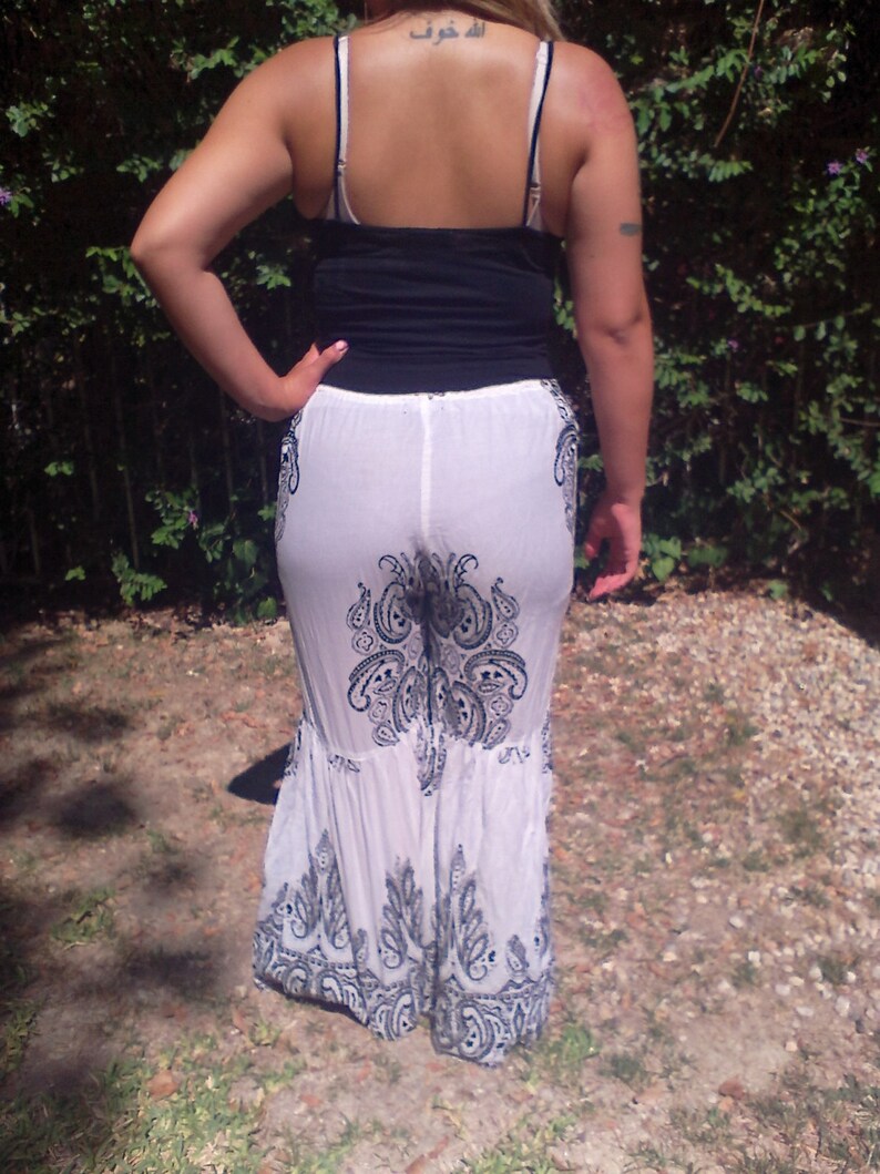 May include: White maxi skirt with a black paisley print. The skirt has a ruffled hem and is made of a sheer fabric.