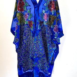 May include: A royal blue velvet shawl with a peacock feather design and floral embroidery. The shawl has a fringe trim and is displayed on a mannequin.