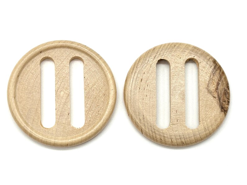 Pode incluir: Dois bot&otilde;es de madeira com um design de fenda dupla. Os bot&otilde;es s&atilde;o de cor castanho claro e t&ecirc;m uma veia de madeira natural.