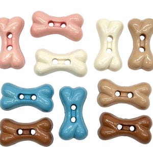 Peut inclure: Dix boutons en plastique en forme d'os de chien de différentes couleurs, dont le rose, le blanc, le marron et le bleu. Les boutons ont deux trous chacun et sont parfaits pour les projets de bricolage.