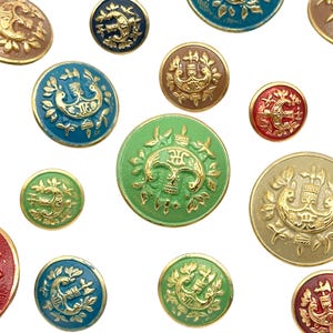 Può includere: Assortimento di bottoni colorati con accenti dorati e disegni intricati. I bottoni presentano una varietà di colori, tra cui verde, blu, rosso e marrone. Ogni bottone ha un disegno dorato al centro, circondato da un bordo decorativo.