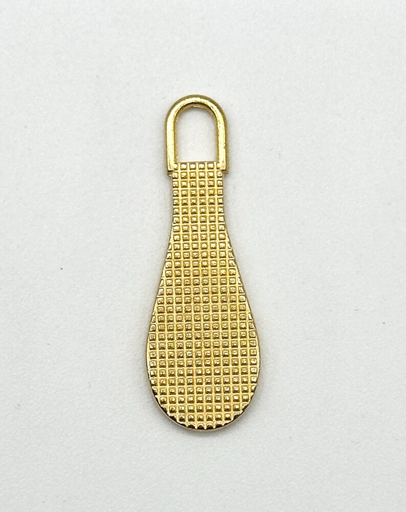 May include: Gold-toned metal zipper pull with a teardrop shape and a textured surface.