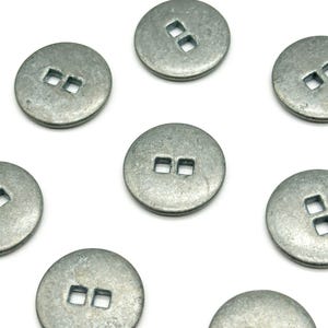May include: A set of eight silver metal buttons with two square holes in the center. The buttons are round and have a slightly textured surface.