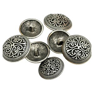 Könnte beinhalten: Sechs silberfarbene Knöpfe mit einem dekorativen, wirbelnden Design. Die Knöpfe haben eine erhabene, runde Form und ein einzelnes Loch zum Nähen.