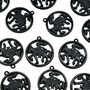 May include: Black metal pendants with a circular design featuring a knight on horseback. Each pendant has a small loop at the top for attaching to a chain or other jewelry component. The pendants are evenly spaced against a white background.