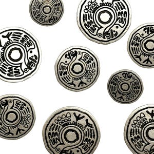 May include: A collection of eight silver-toned metal discs with a black design of a stylized bird with outstretched wings. The design is repeated on each disc, but the size of the discs varies.