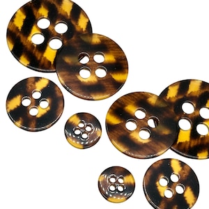 May include: A selection of round buttons featuring a tortoiseshell design in brown and yellow hues. The buttons are of various sizes and have either two or four holes for sewing.