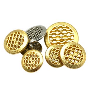 May include: A set of five gold-toned cufflinks with a geometric pattern. The cufflinks are round and have a textured surface.