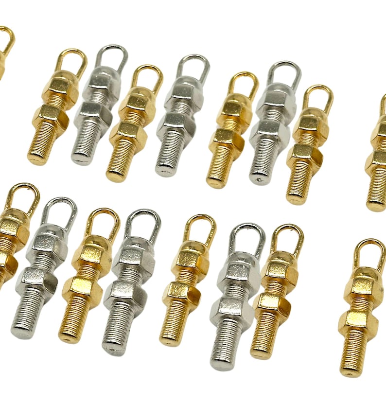 May include: A collection of 18 gold and silver metal charms shaped like nuts and bolts with a loop at the top.