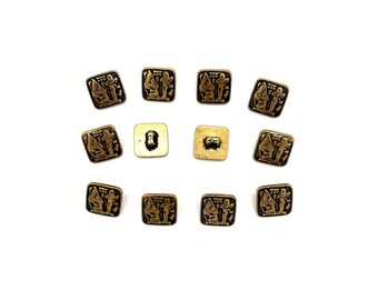 May include: Twelve gold-toned square buttons with a raised design of two figures. The buttons have a black outline and a slightly textured surface.